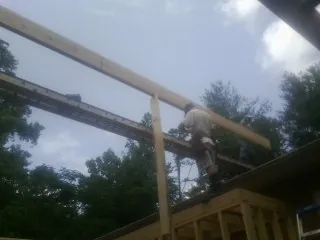 Carpenter setting a ridge beam over a new addition frame — Ice Dam Removal by Roofing Brothers in Burnett