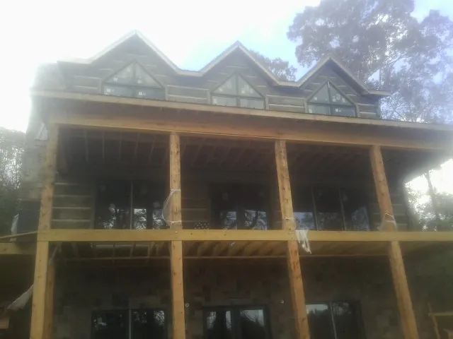 Dormers and porch framing on a large log home under construction — Roof Coating work by our crew in Burnett