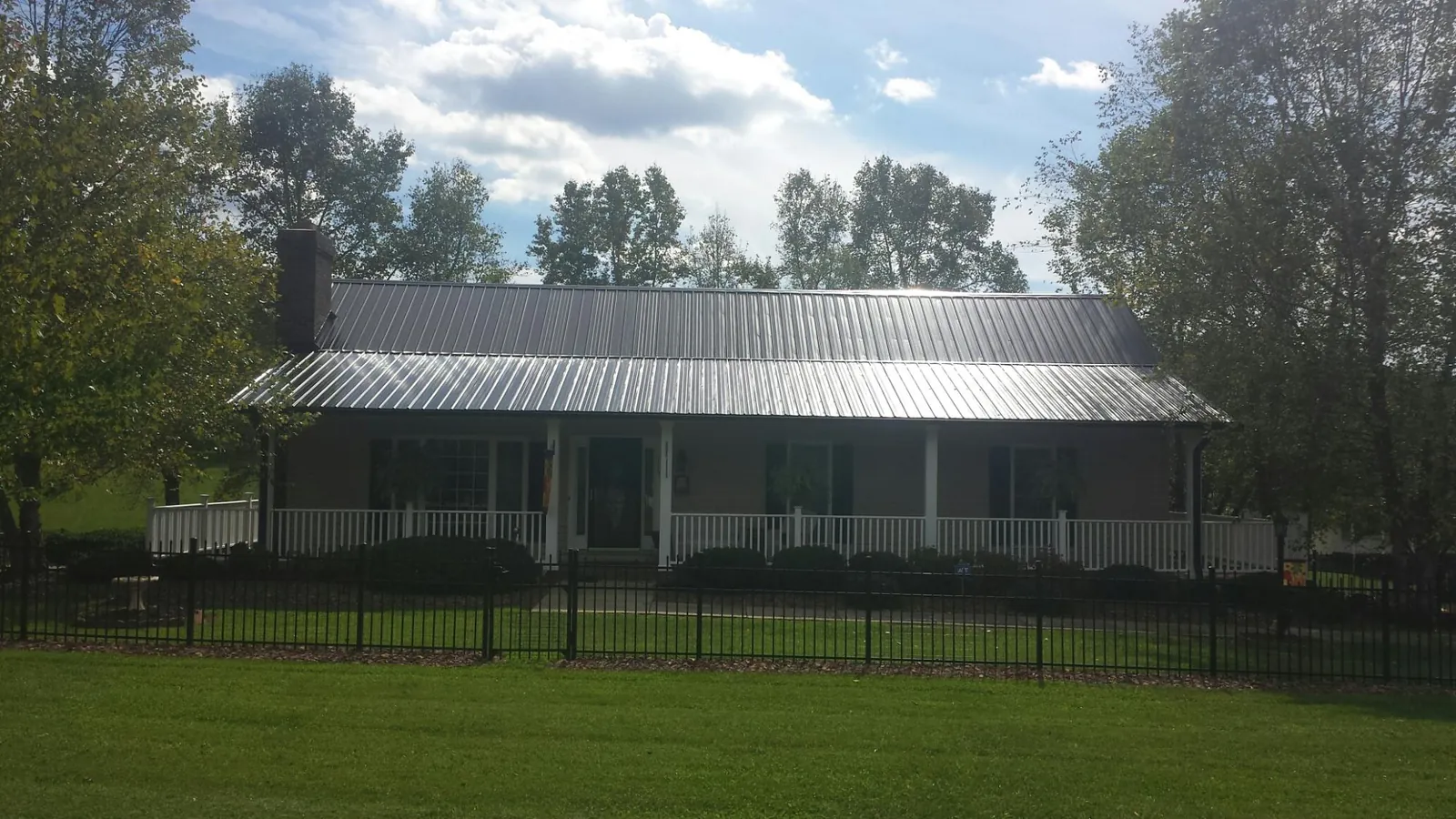 Gray metal roof on a brick ranch with a full width front porch — Gutter Guard Installation work by our crew in Burnett