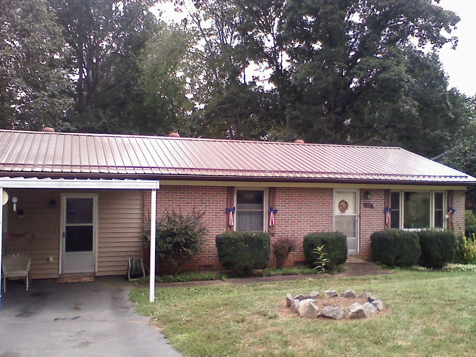 Bronze metal roof and carport on a brick ranch home — Roof Repair work by our crew in Burnett